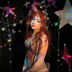 a woman with red hair and makeup is posing in front of stars