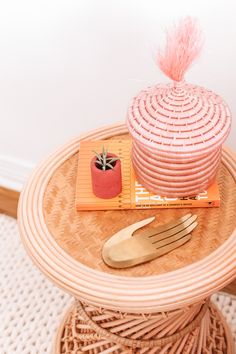 a table with a basket, fork and knife sitting on top of it next to a potted plant