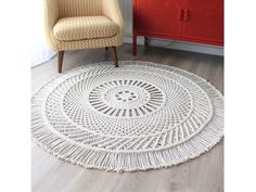 a white rug with fringes on the floor next to a chair and red cabinet