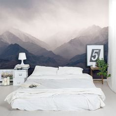 a bedroom with a large mountain mural on the wall and bed in front of it