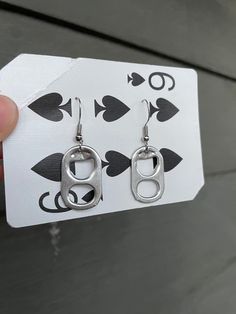 a pair of silver earrings sitting on top of a playing card with an ace symbol