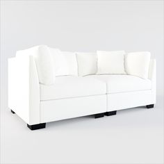 a white couch with four pillows on it's back and two sides facing each other