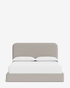 an upholstered bed with white sheets and pillows