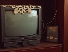 an old fashioned television sitting on top of a wooden shelf next to a remote control