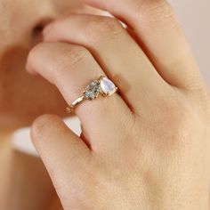 a woman's hand with a ring on it that has two stones in the middle