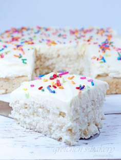 a slice of cake with white frosting and sprinkles