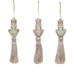 three ornaments with tassels hanging from the top and bottom, one wearing a crown