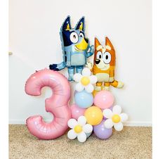 some balloons that are on the ground near a number three sign and an orange cat