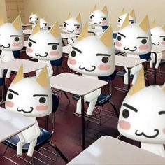 a classroom filled with lots of white desks covered in paper cats head masks on top of them