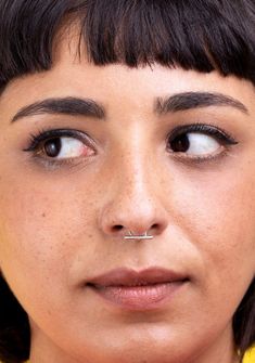 a close up of a woman with piercings on her nose and nose ring in front of her face