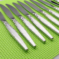 a set of six knives sitting on top of a green mat next to each other