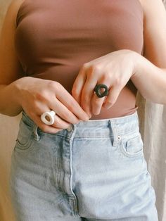 a woman is holding onto her jeans with an object in her hand while wearing a ring