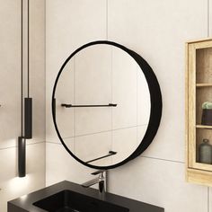 a bathroom with a round mirror on the wall and black sink in front of it