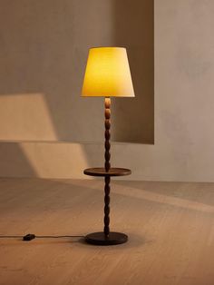 a lamp that is on top of a wooden table with a yellow shade over it