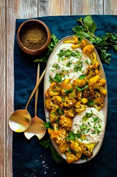 a platter filled with cauliflower covered in cream sauce and garnished with parsley