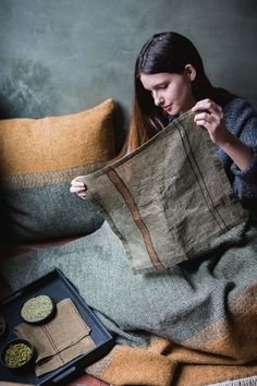 a woman sitting on a couch holding up a piece of cloth next to some food