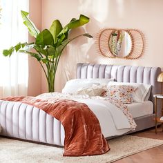 a bedroom with a bed, mirror and potted plant on the side of the bed