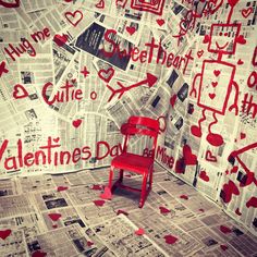 a red chair sitting in front of a wall covered with paper cutouts and hearts