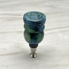 a blue and green vase sitting on top of a white table