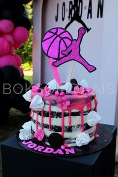 a birthday cake decorated with pink and black icing, on top of a table