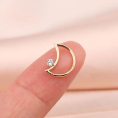 a person's finger with a gold crescent ring on it and a diamond in the middle