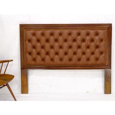 a brown leather headboard sitting on top of a wooden table next to a chair