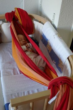 a baby in a crib with red, orange and yellow blankets