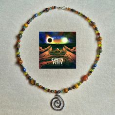 An earthy crystal beaded necklace inspired by Greta Van Fleet's debut album: Anthem of The Peaceful Army 𖦹 We have created this necklace to imitate the beautiful imagery created for this album. We have tried to include each aspect of the album cover art 🌎 We have used crystals such as carnelian, tiger's eye, lapis lazuli, Indian agate. We also included Japanese ceramic and glass beads, czech glass beads and a beautiful large silver swirl charm 🪷 🕊 The necklace is made to around 15 inches. If Earthy Beaded Necklace, Earthy Beaded Necklace For Gift, Earthy Beaded Necklace For Gifts, Earthy Agate Beaded Necklaces, Greta Can Fleet Jewelry, Anthem Of The Peaceful Army, Earthy Necklace, Crystal Beaded Necklace, Greta Van Fleet