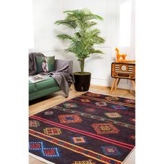 a living room with a green couch, rug and potted plant in the corner