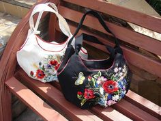 two purses sitting on top of a wooden bench next to each other and one has flowers painted on it