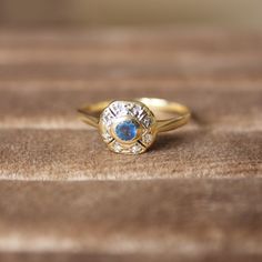 a gold ring with a blue stone in the center on top of a wooden surface