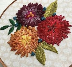 a close up of a embroidery on a piece of cloth with flowers in the middle