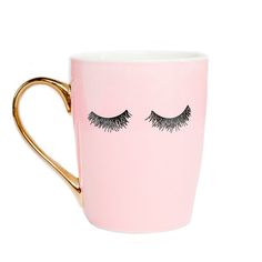 a pink coffee cup with eyelashes on the side and gold rimmed mug in front