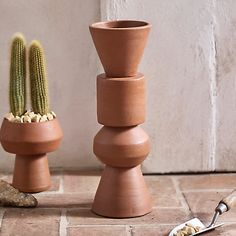 three clay vases sitting on top of a tile floor next to a small cactus