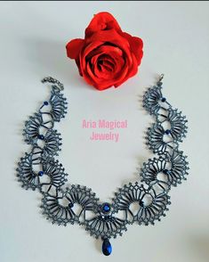 the necklace is next to a red rose on a white surface with text that reads aria magic jewelry