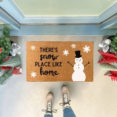 a person standing in front of a door mat that says there's snow place like home