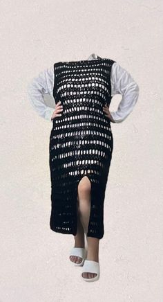 a woman is standing in the air with her arms behind her back, wearing a black and white crochet dress