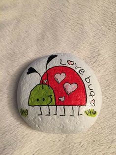 a painted rock that says love bug with two little bugs on it