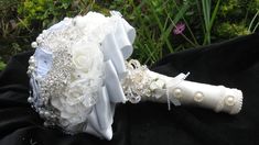 the bridal bouquet is sitting on top of a black cloth in front of some flowers