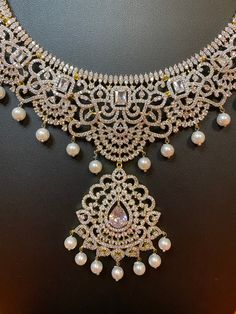 Indulge in luxury with our exquisite South Indian Haaram necklace. Adorned with CZ American Diamonds, it is the perfect accessory for weddings, parties, and gifting. Elevate your Indian outfit, be it a silk saree or gown, with this long and elegant necklace. A must-have for every sophisticated and exclusive wardrobe. This jewellery set includes a necklace and matching earrings. Jewellery Care- Keep the jewellery dry, avoid contact with perfumes and water. Elegant Hand Set Lehenga For Wedding, Dazzling Bridal Necklace For Reception, Bollywood Style Diamond Kundan Necklace For Wedding, Elegant Silver Lehenga For Formal Occasions, Elegant White Lehenga With Intricate Design, Diamond Bridal Necklace With Stone Work For Parties, Formal Bridal Necklace With Tilla And Diamonds, Elegant Silver Lehenga With Stone Work, Formal Bridal Necklace With Diamond And Tilla