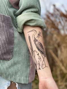 a woman with a bird tattoo on her left arm and the other hand is holding an object