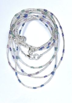 Offered here is a handcrafted minimalist style beaded necklace featuring an assortment of tiny (11/0 size) high quality metallic blue, green, pink, and purple colored glass Japanese Miyuki and Toho seed beads and silver colored smooth Japanese tube beads. 11/0 beads are approximately 2mm in size. The tube beads are approximately 6mm to 7mm in size. The pretty shimmery colors give this necklace a striking boho appearance, simple and perfect for any style and every day. Each is completed with a si Layered Necklaces Boho, Necklaces Boho, Layering Necklaces, Tiny Beads, Stylish Necklace, Crystal Suncatchers, Necklace Beaded, Beading Wire, Metallic Blue