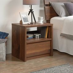 a bed room with a neatly made bed and a night stand on the side table