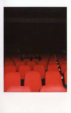 an empty auditorium with rows of red chairs