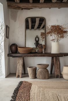 a table with vases and bowls on top of it in front of a mirror