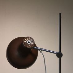 a desk lamp with a brown shade on it's side and a white wall in the background