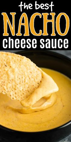 a tortilla chip being dipped with nacho cheese sauce in a black bowl