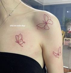 two butterflies on the back of a woman's shoulder, both with red ink