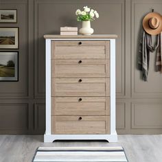 a white and brown chest of drawers in a room with pictures on the wall behind it