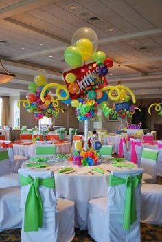 a room filled with tables covered in white linens and colorful balloons